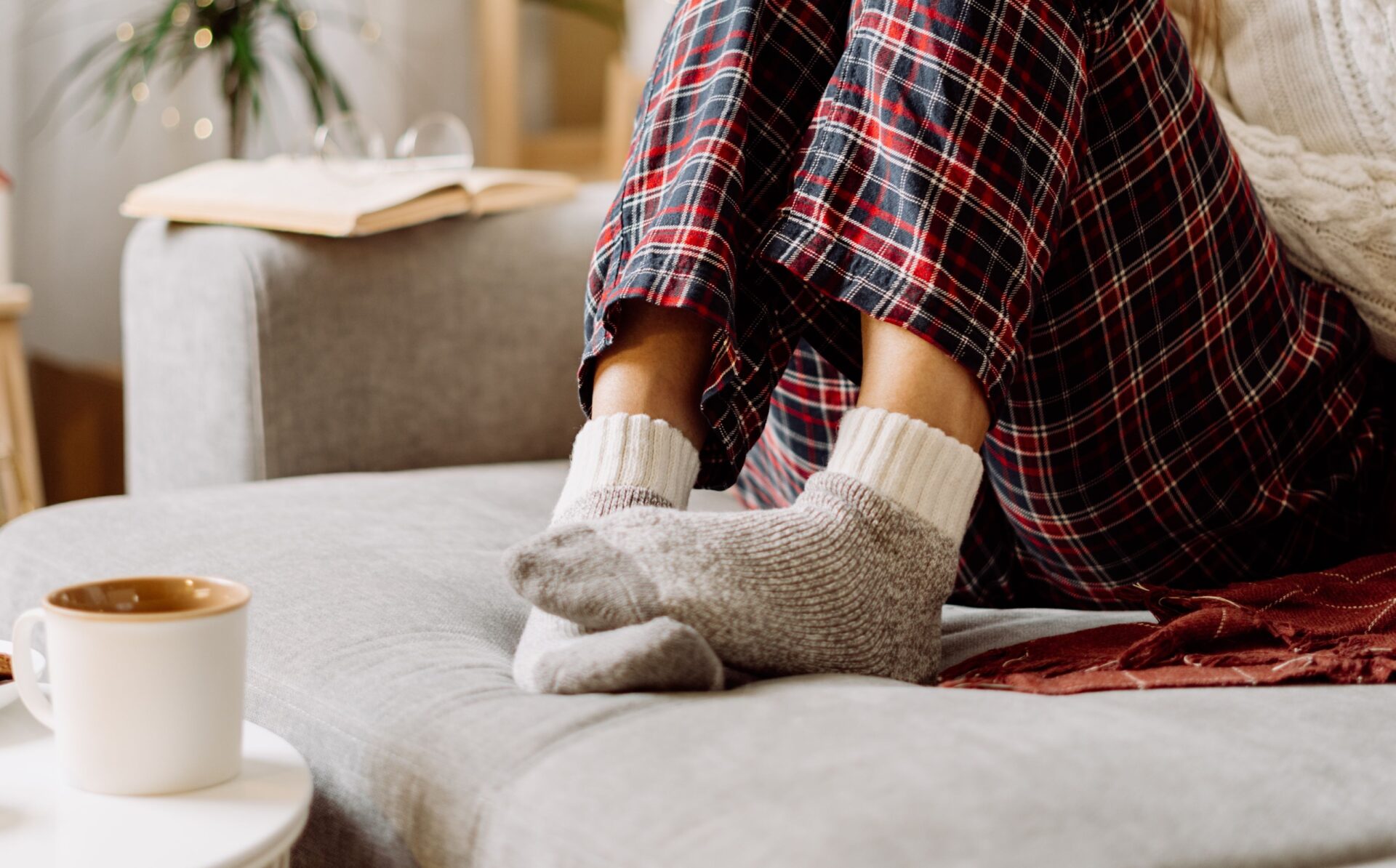 Vrouw met pyjamabroek en wollen sokken op de bank