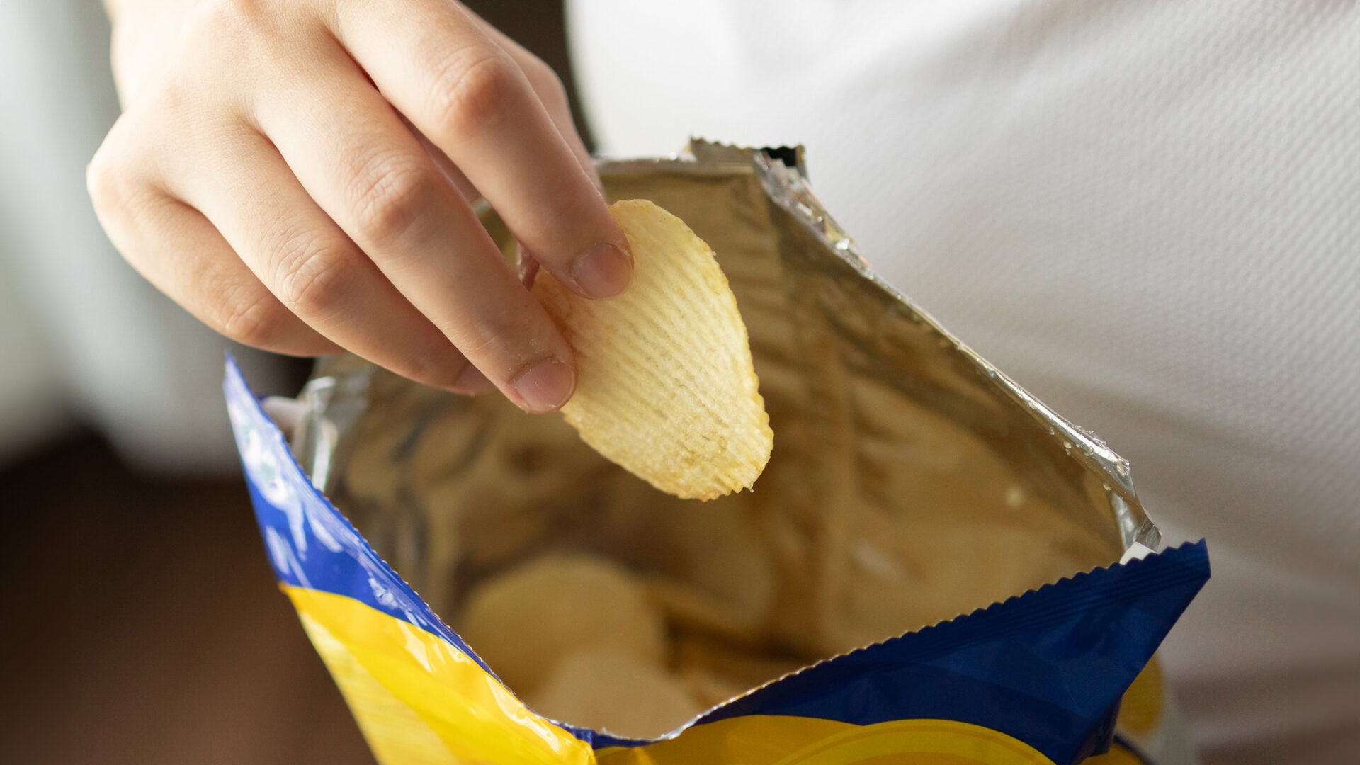 Hand pakt chips uit een zak