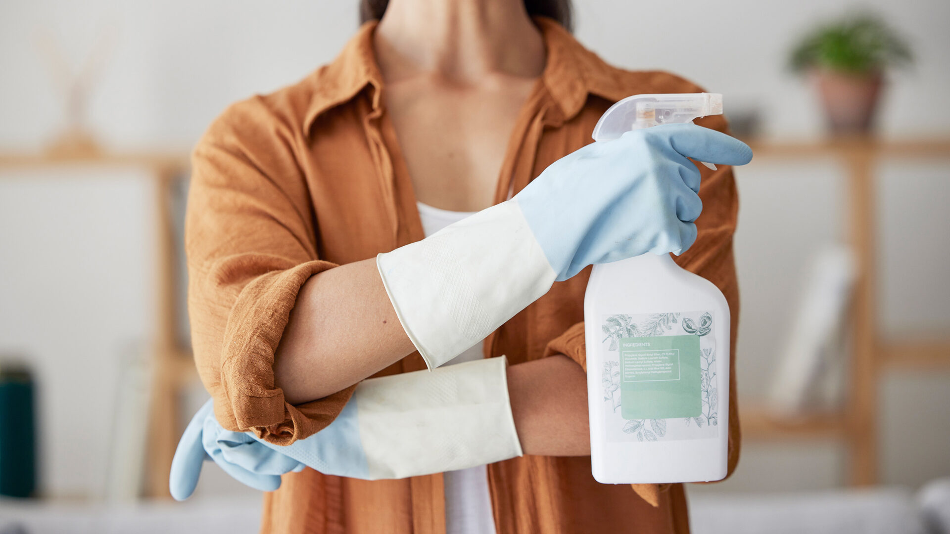 vrouw met schoonmaakhandschoenen en schoonmaakmiddel in handen