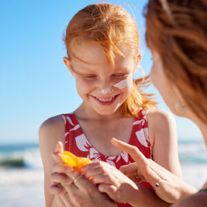 Vrouw en kind met zonneproduct op het strand