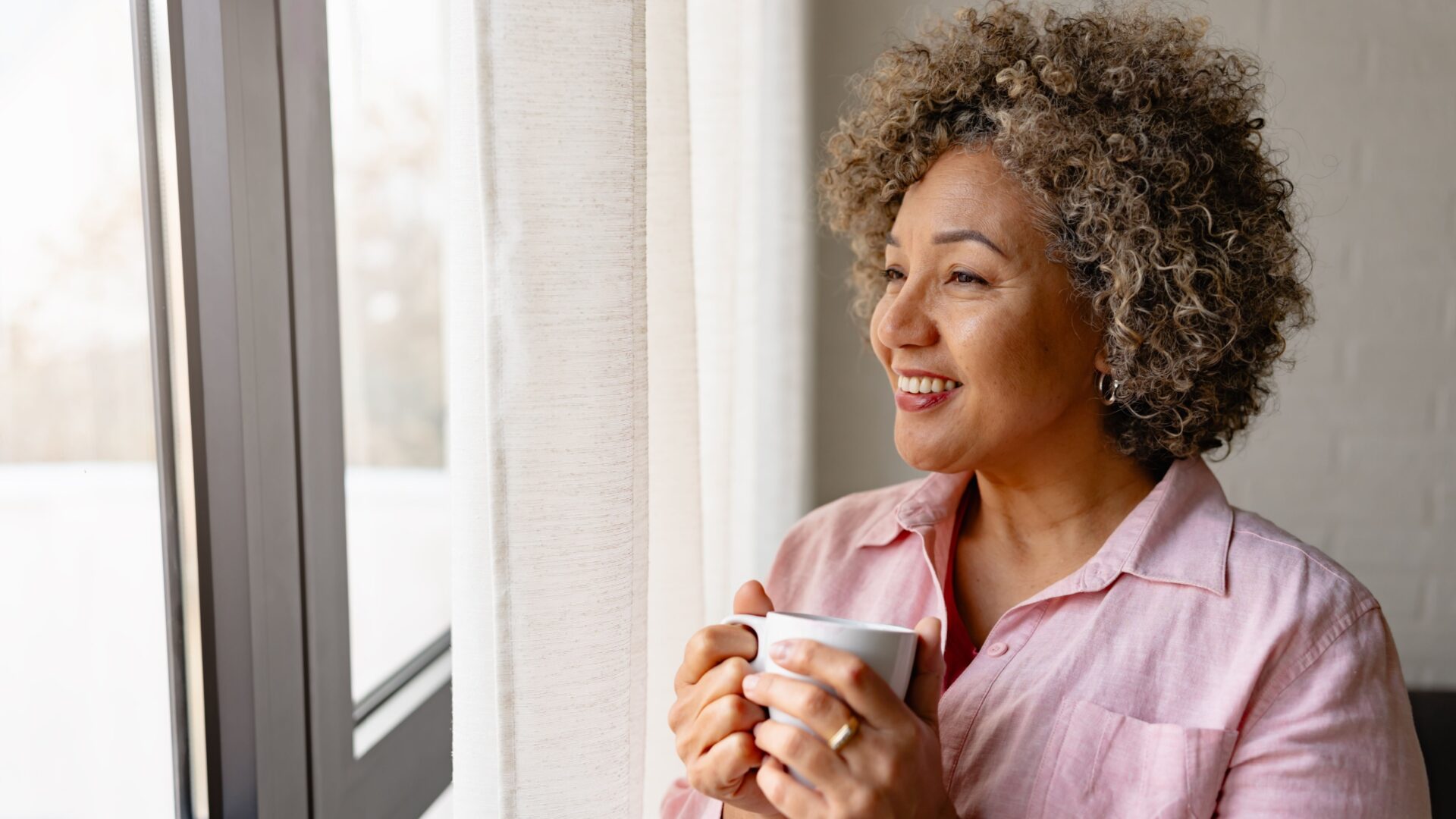 Vrouw kijkt lachend uit het raam