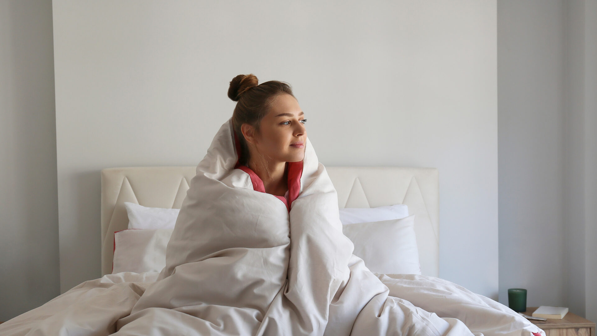 vrouw met dekens om haar heen rechtop in bed