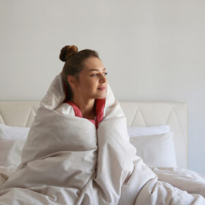 vrouw met dekens om haar heen rechtop in bed