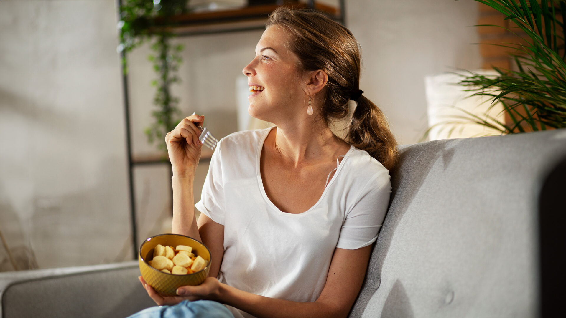 Vrouw op de bank met een schaaltje fruit