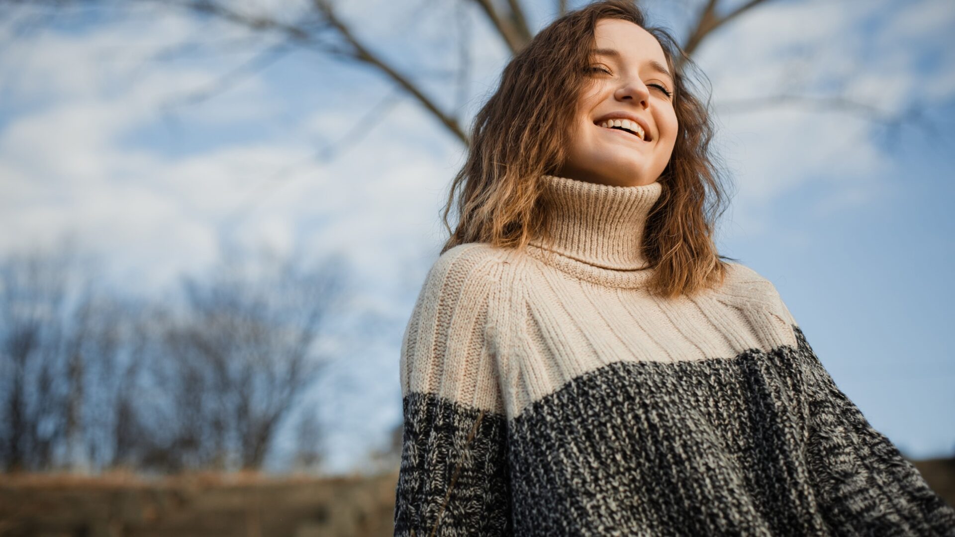 vrouw lachend met een warme trui buiten