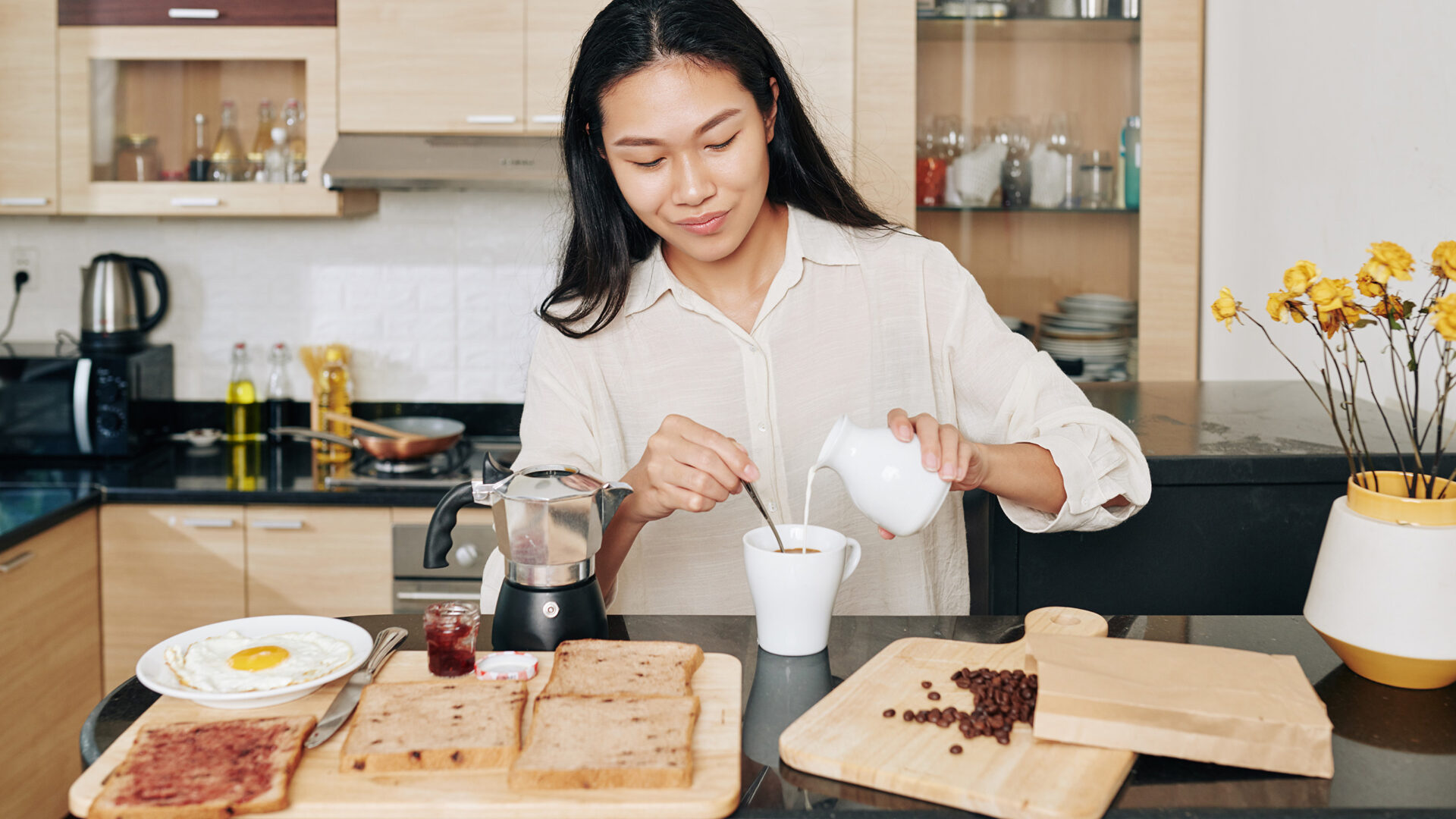 Vrouw schenkt melk in de koffie