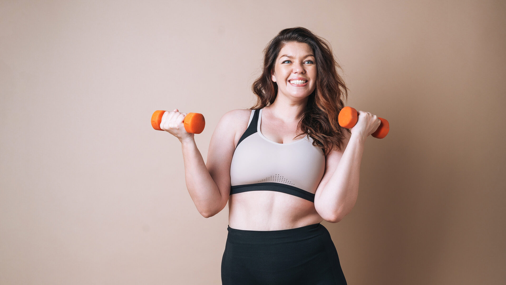 Vrouw in sporttop met fitnessgewichtjes in haar handen