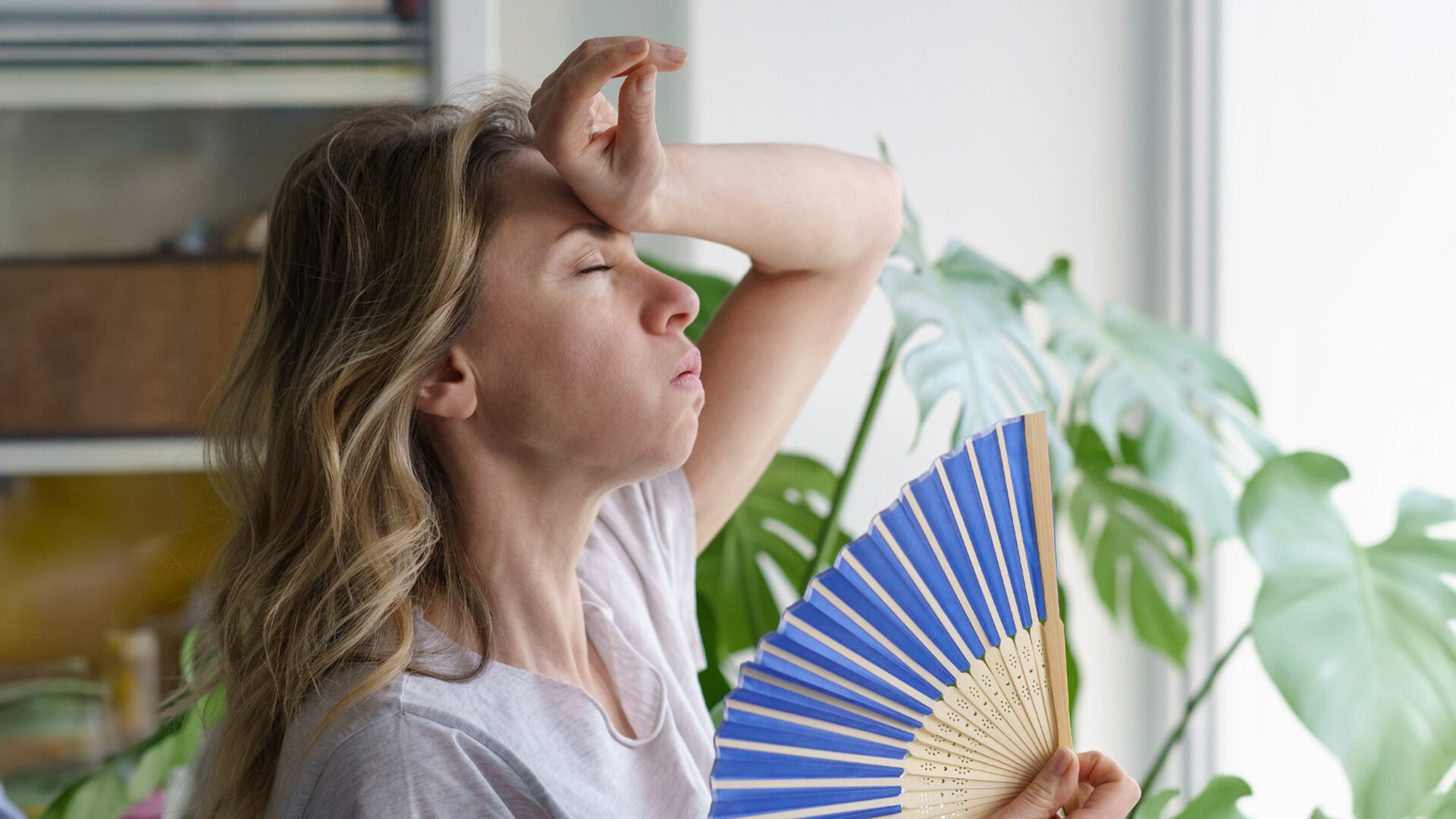 Vrouw met een waaier en een hand op haar voorhoofd