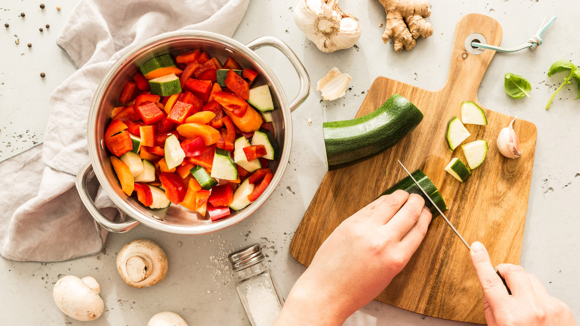 Courgette snijden naast een pan vol gesneden groenten