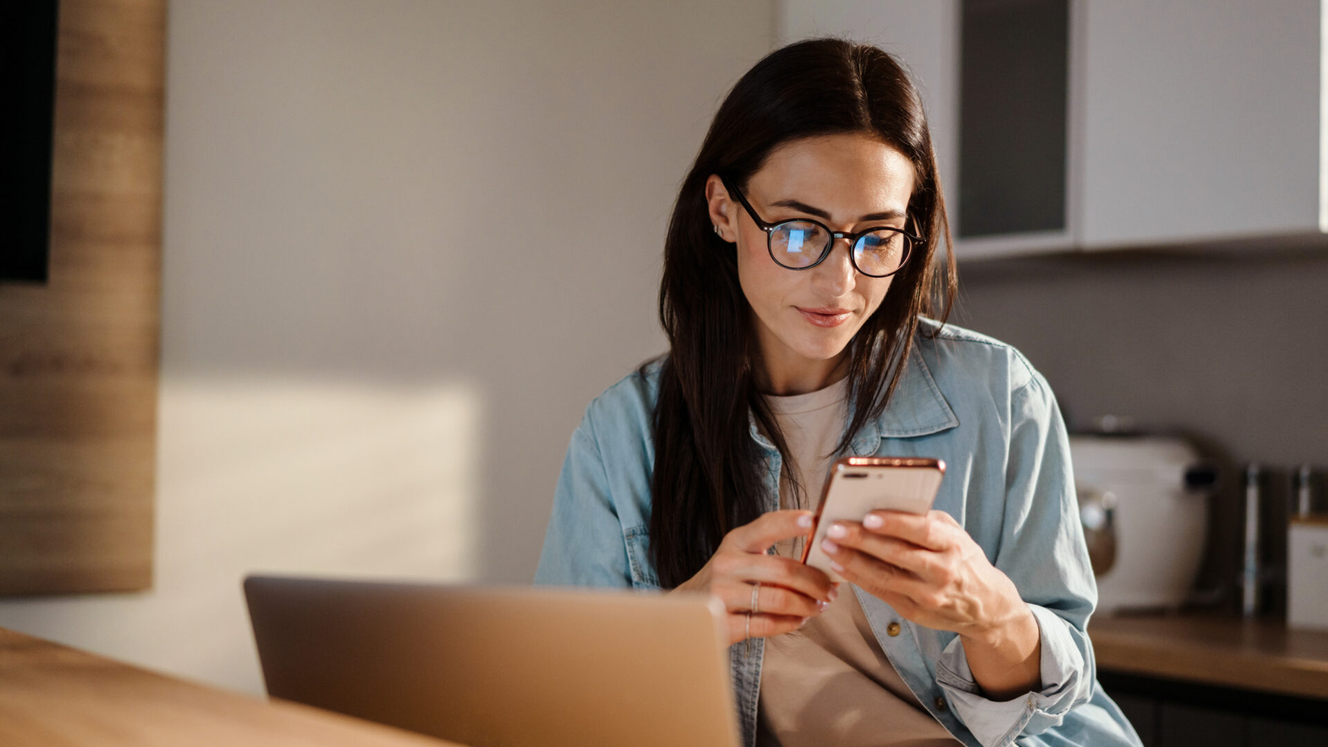 Vrouw met laptop en telefoon in handen