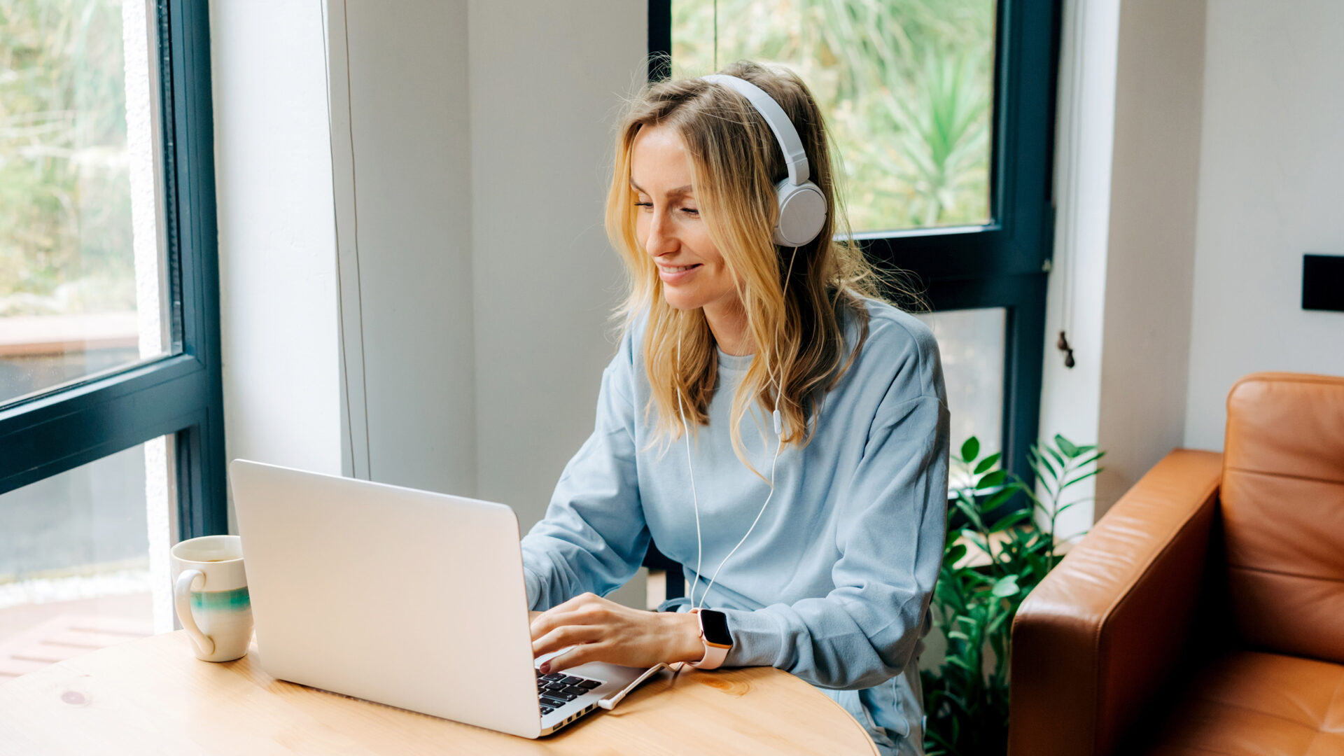 Vrouw met koptelefoon achter laptop in huis