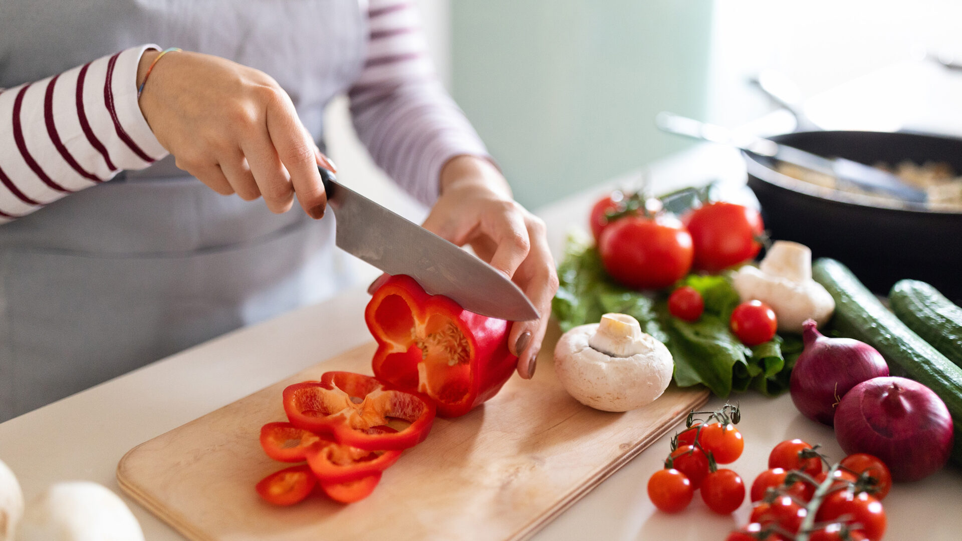 Vrouw snijdt paprika op houten plank