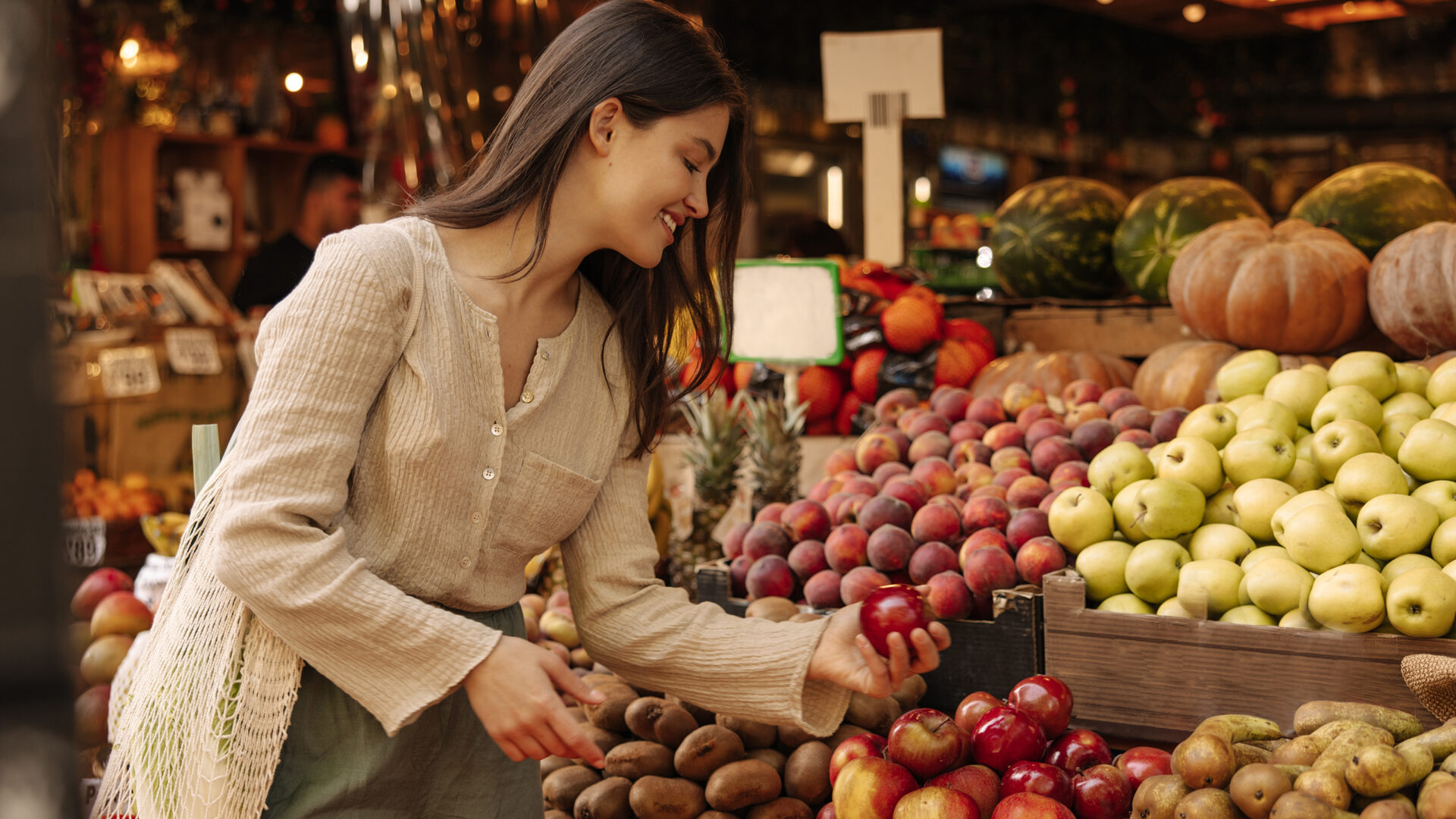 Vrouw pakt appel bij fruitkraam