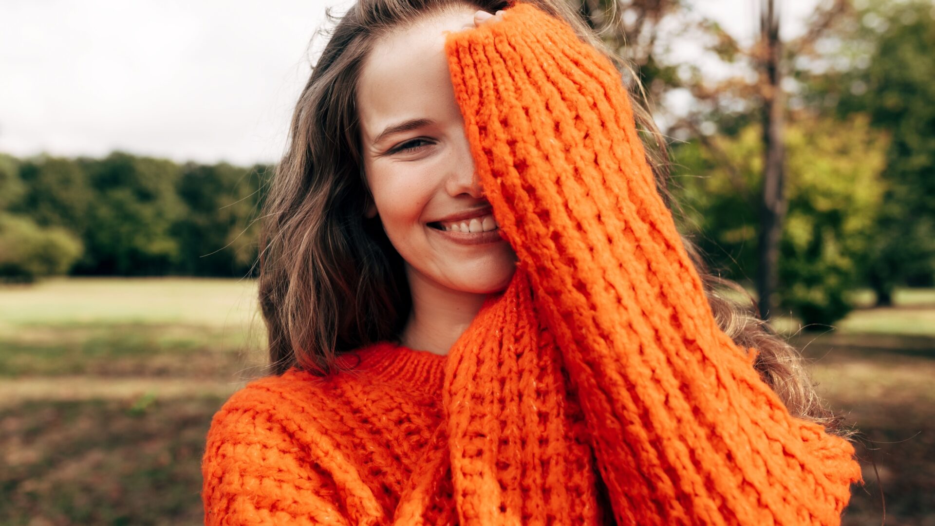 Vrouw met een rode trui houd een hand voor haar gezicht