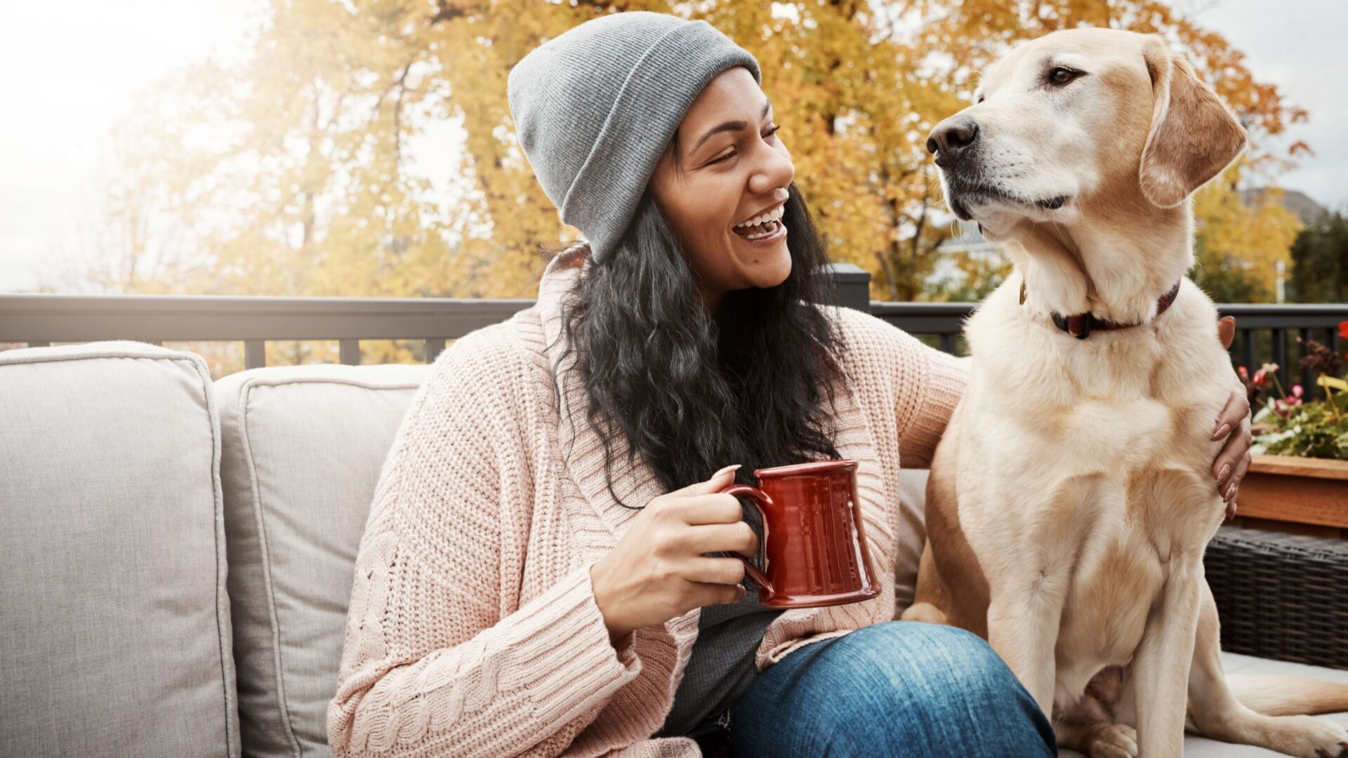 Vrouw met mok en hond op een tuinbank