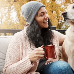 Vrouw met mok en hond op een tuinbank