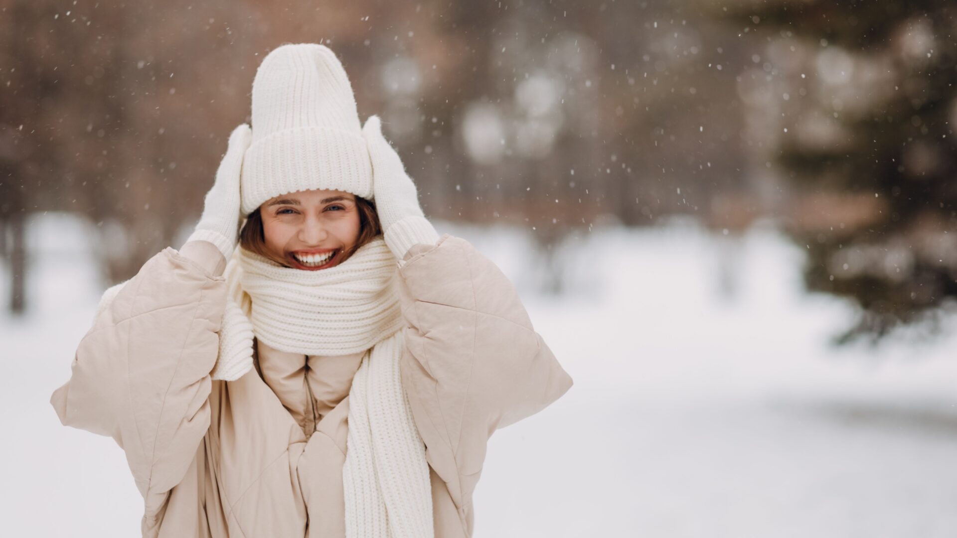 Vrouw met handschoenen, dikke jas en muts op in de sneeuw