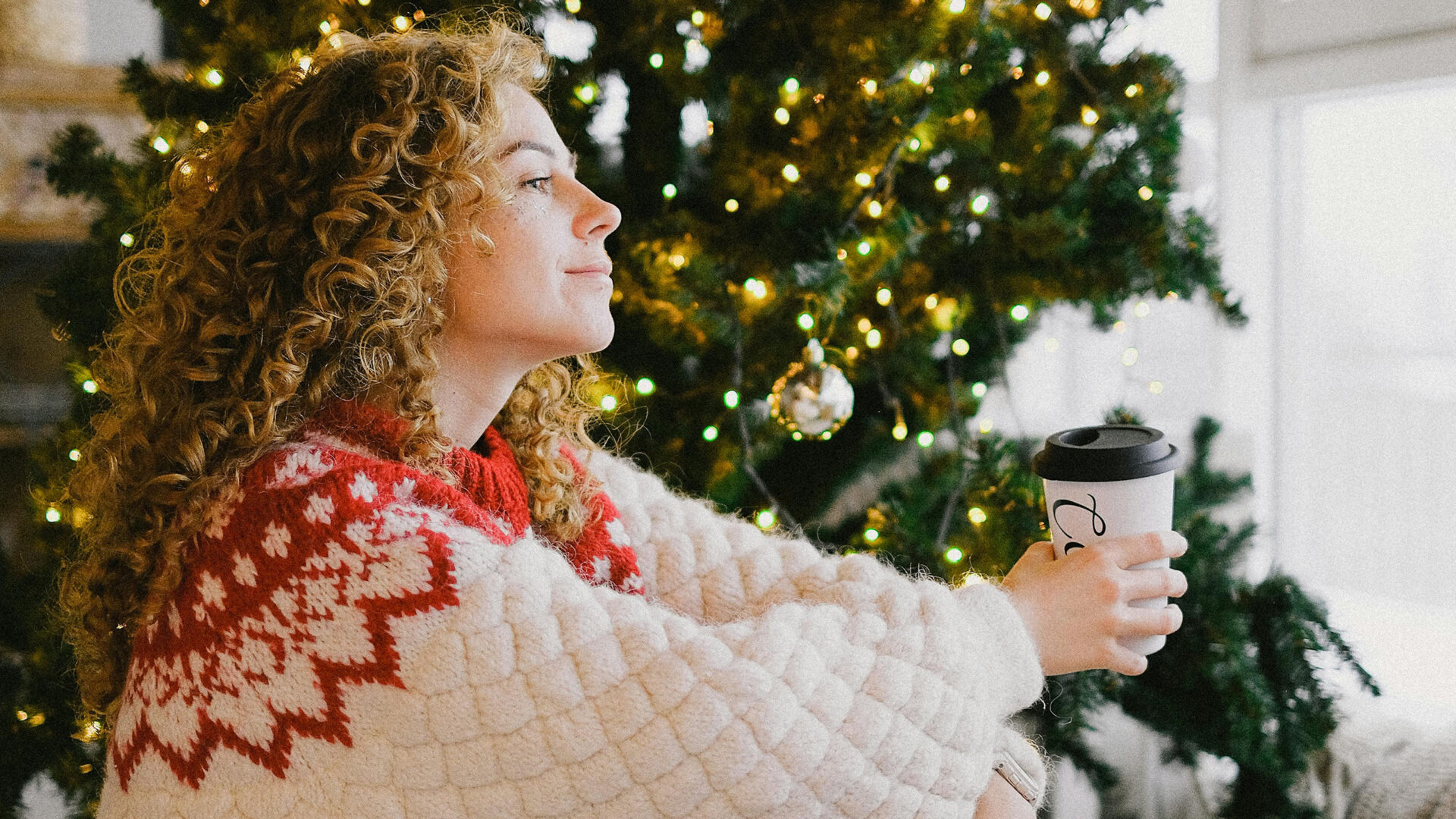 vrouw met kop koffie bij de kerstboom