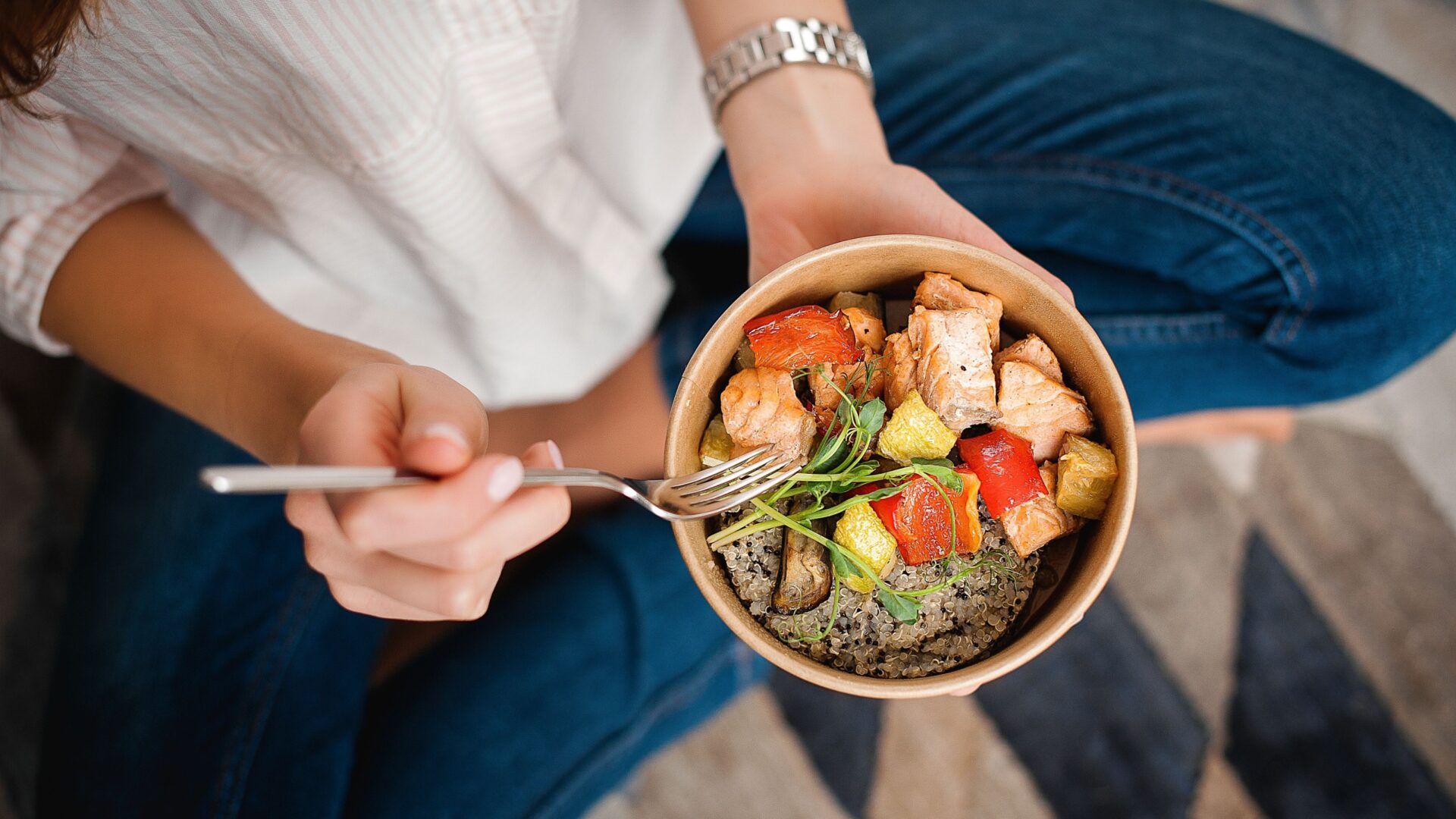 Vrouw in kleermakerszit met poké bowl