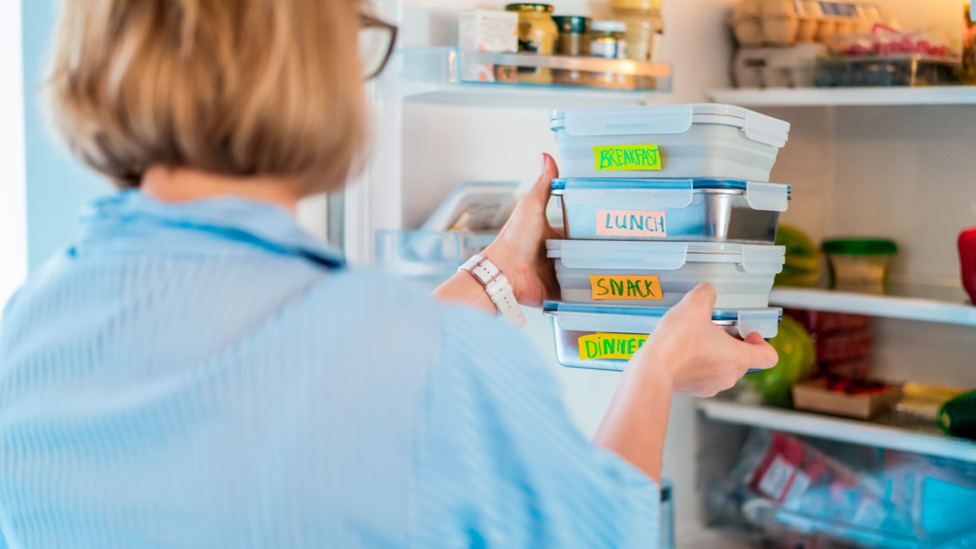 Vrouw zet bakjes eten in de koelkast