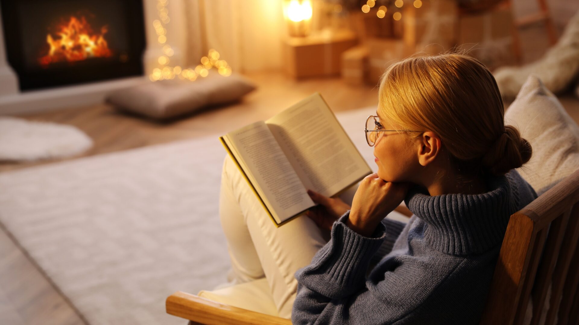 Vrouw leest boek voor de kachel