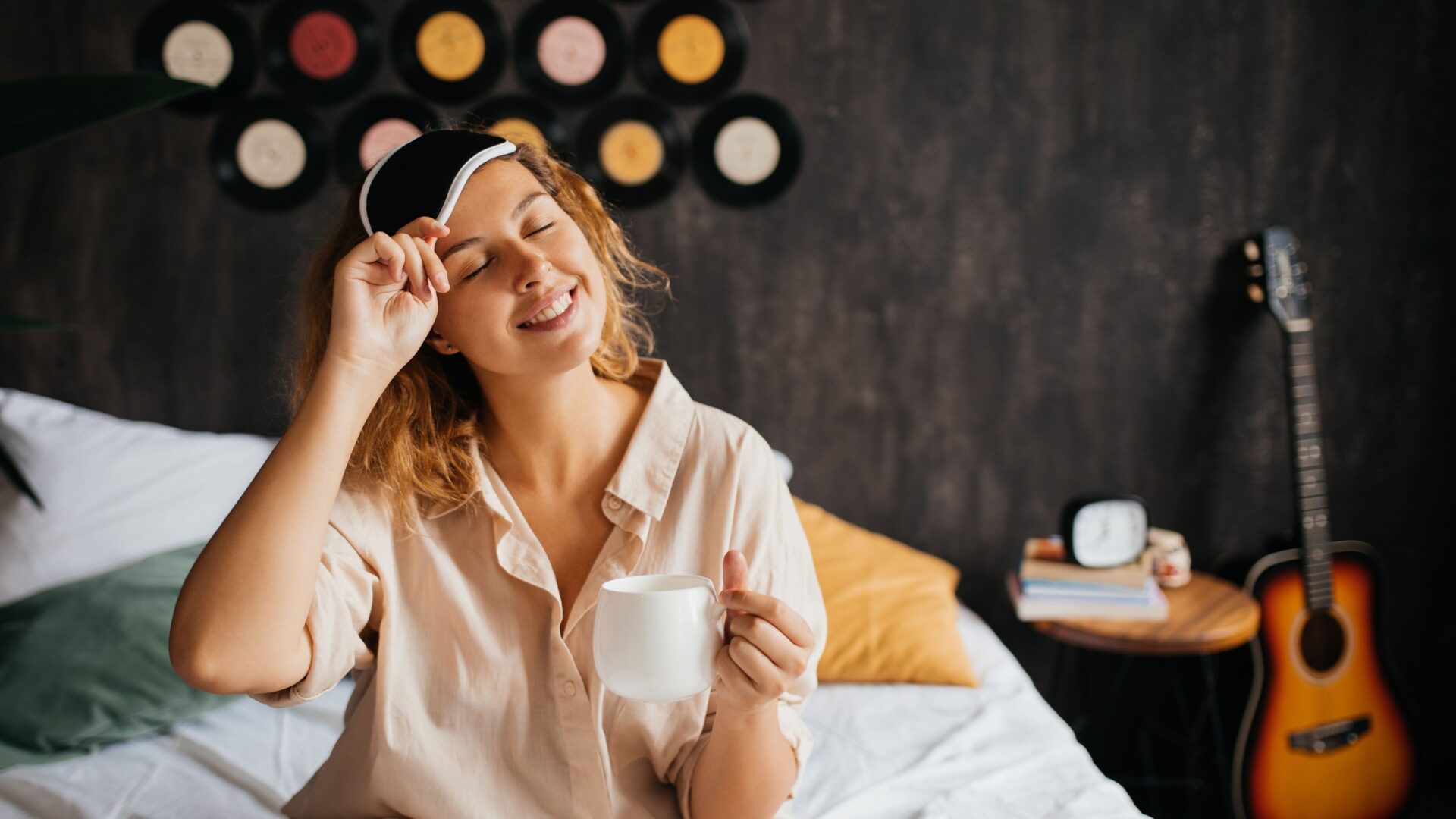 Vrouw in bed met mok en slaapmasker